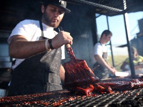 A worker at the Jack the RIbber stand slathers some meat Saturday during Ribfest at the Riverfront. (KRISTIE PEARCE/The Windsor Star)