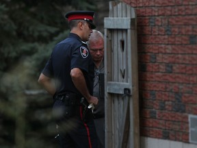 A Windsor police officer, left, and a Windsor police detective inspect the dead body of a male in his thirties at 3167 Donnelly Street, Wednesday, August 29, 2012.  (DAX MELMER/The Windsor Star)