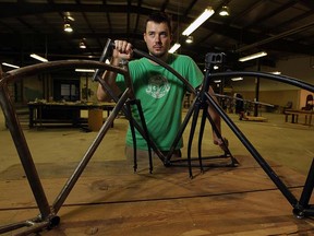 Calgary native Zak Pashak holds up some prototype bicycle frames at his Detrot Bikes company on Aug. 3, 2012. (The Windsor Star / TYLER BROWNBRIDGE)