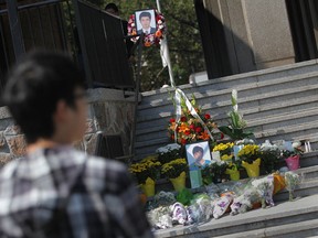 A mourner looks over a memorial to Shaowen Zhang, the Chinese student killed in a fiery crash on the E.C. Row expressway on Aug. 21, 2012. Photographed Aug. 24, 2012 outside Chrysler Hall on the University of Windsor campus. (Dax Melmer / The Windsor Star)