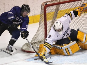 Lancers goalie Parker Van Buskirk, right, pokes the puck away from UOIT's Kevin George at Windsor Arena. (DAN JANISSE/The Windsor Star)