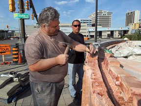 Mason Gianna Sfalcin, left, and assistant John Fuerth dismantle Sfalcin's wall of artwork which depicts images of Windsor on Wyandotte Street East at Goyeau Avenue on Sept. 25, 2012.  The wall must be removed brick by brick and stored.  Land in the area is being cleared for the new tunnel plaza project. (NICK BRANCACCIO/The Windsor Star)