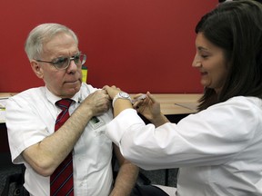 Medical officer of health, Dr. Allen Heimann receives his flu shot from public health nurse Sandy Kozar, following a press conference where he announced flu vaccines are readily available.  Everyone except those with certain medical conditions should get the vaccine Friday September 28, 2012.   (NICK BRANCACCIO/The Windsor Star)