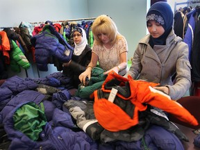 Coats for Kids co-ordinator, June Muir, centre, helps Marah Damdoum, left, of the An-Noor school and Aysenur Aktas of the Al-Hijra school, unpack  coats they collected for the Unemployed Help Centre in Windsor on Nov. 21, 2011.(DAN JANISSE/The Windsor Star)