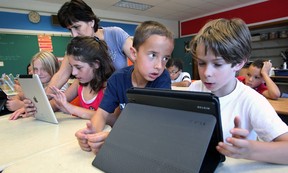 St. John's Elementary School pupils Kordelia Murphy, left, Vanessa Stephenson, Alex Rafael-Rawlings and Nick Putt use iPads while working with teacher Lori Market. The use of IPads as a teaching tool has been a key element of higher test scores.