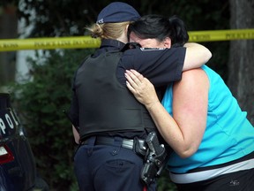 An Amhersburg police officer consoles a friend of the victims at the scene of an early morning house fire at 216 Richmond Street in Amerherstburg, Ont., where two people died, Sunday, Sept. 9, 2012. (DAX MELMER/The Windsor Star)