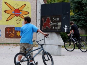 Young people ride bikes past South Secondary School, where 8 students were charged in a bullying case in London, Ont., on  Oct. 19, 2012. THE CANADIAN PRESS/Dave Chidley