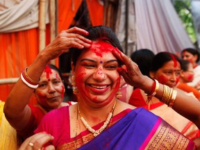 A Hindu woman reacts as others apply vermillion powder on her during Durga Puja festivities in New Delhi, India, Wednesday, Oct. 24, 2012. The festival commemorates the slaying of a demon king by lion-riding, ten armed goddess Durga, marking the triumph of good over evil. (AP Photo/Rajesh Kumar Singh