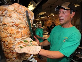 Walid Abouelella (R) slices chicken shawarma while Badar Falah serves customers at Shawarma Palace in Windsor, Ont. on Oct. 31, 2012. (Nick Brancaccio / The Windsor Star)