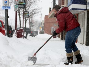 An Essex shopkeeper shovels the sidewalk in front of her store in the  morning after a snowfall on Feb. 2, 2011.  (Windsor Star files)