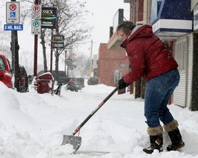 An Essex shopkeeper shovels the sidewalk in front of her store in the  morning after a snowfall on Feb. 2, 2011.  (Windsor Star files)