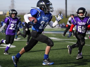 Izaiah Chheng, centre, rushes for a first down for the Tim Hortons Panthers against the Tim Hortons Vikings in the Windsor Minor League Football Association's Day of Champions at Alumni Field Saturday. (DAX MELMER/The Windsor Star)