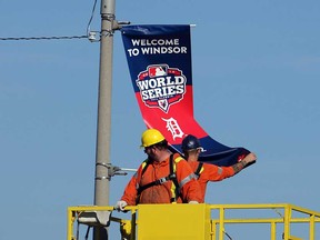 In this file photo, workers install a banner on a downtown lampost celebrating the Detroit Tigers World Series run. The city expects hotels to be full and downtown restaurant and bars to be buzzing when the Tigers host the San Francisco Giants for three games at Comerica Park on Saturday, Sunday and Monday. City council agreed this week to spend $10,000 on banners throughout the downtown.(TYLER BROWNBRIDGE / The Windsor Star)