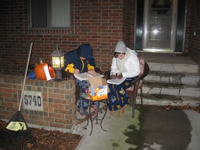 Lise Jacobs, first year University of Windsor student, and brother Evan Jacobs, senior at Sandwich Secondary, doing double duty- optimizing their time studying as they handout Halloween candy to the local kids. (Peter Jacobs/Special to The Star)