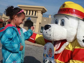 Kristina Gawne, 4, left, gets a hug from Sparky after donating a toy doll to Sparky's Toy Drive at Windsor Crossing, Saturday, Nov. 17, 2012.  (DAX MELMER/The Windsor Star)