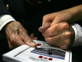 A student holds the hand of a veteran during Remembrance Day ceremonies. (Postmedia News files)