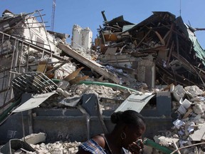 In this file photo a woman keeps her face covered as she passes a destroyed building in downtown Port-au-Prince following the earthquake in January 2010. (Kier Gilmour/Postmedia News)