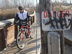 Graffiti remains painted on a sign as Domenic Aversa walks his bicycle over the bridge at Vince Marcotte Park in LaSalle, Ontario on November 15, 2012. (JASON KRYK/The Windsor Star)