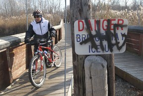 Graffiti remains painted on a sign as Domenic Aversa walks his bicycle over the bridge at Vince Marcotte Park in LaSalle, Ontario on November 15, 2012. (JASON KRYK/The Windsor Star)