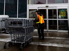 A grocery store employee brings in shopping carts in Toronto on Feb. 18, 2009.(Canadian Press files)