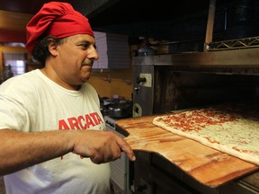 Bob Abumeeiz, owner of Arcata Pizzeria on Dougall Avenue, takes a pizza out of the oven in this 2011 file photo.  (DAX MELMER / The Windsor Star)