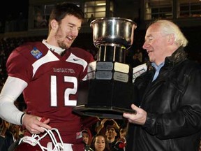 South Woodslee's Kyle Quinlan, left, receives the Mitchell Bowl trophy from Doug Mitchell, after defeating the University of Calgary Dinos in CIS football action in Hamilton, Ontario, on Saturday, Nov. 17, 2012. (Dave Chidley/The Canadian Press)