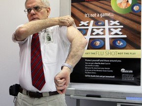 Medical officer of health, Dr. Allen Heimann, rolls up his sleeve to receive a flu shot during a news conference in September at which he announced flu vaccines are readily available.  Everyone except those with certain medical conditions should get the vaccine, he said.   (NICK BRANCACCIO/ Windsor Star file)