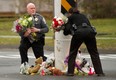 Police officers remove flowers from a busy intersection December 16, 2012 in Newtown, Connecticut. The officers said they were afraid the memorial may cause a traffic hazard. The people of Newtown, soon to be joined by President Barack Obama, poured into churches Sunday to pray for the 20 children and seven adults slaughtered in one of the worst ever US shooting massacres. The small Connecticut town led the nation in mourning 48 hours after Adam Lanza burst into Sandy Hook Elementary School and murdered two roomfuls of six- and seven-year-old children, the school principal and five other female staff. From early Sunday churches filled and the town Christmas tree became an impromptu place of remembrance, with people pausing every few minutes to pray and cross themselves under a light snowfall.   AFP PHOTO/DON EMMERT