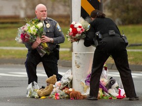 Police officers remove flowers from a busy intersection December 16, 2012 in Newtown, Connecticut. The officers said they were afraid the memorial may cause a traffic hazard. The people of Newtown, soon to be joined by President Barack Obama, poured into churches Sunday to pray for the 20 children and seven adults slaughtered in one of the worst ever US shooting massacres. The small Connecticut town led the nation in mourning 48 hours after Adam Lanza burst into Sandy Hook Elementary School and murdered two roomfuls of six- and seven-year-old children, the school principal and five other female staff. From early Sunday churches filled and the town Christmas tree became an impromptu place of remembrance, with people pausing every few minutes to pray and cross themselves under a light snowfall.   AFP PHOTO/DON EMMERT