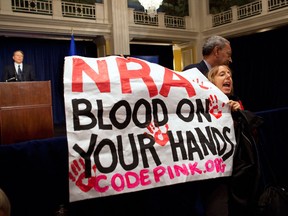 Activist Medea Benjamin, of Code Pink, is led away by security as she protests during a statement by National Rifle Association executive vice president Wayne LaPierre, left, during a news conference in response to the Connecticut school shooting on Friday, Dec. 21, 2012 in Washington. The National Rifle Association broke its silence Friday on last week's shooting rampage at a Connecticut elementary school that left 26 children and staff dead. (AP Photo/ Evan Vucci)