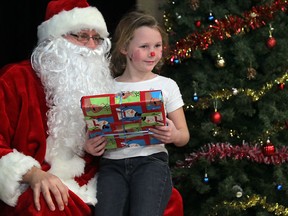 Jylynn Legros, 7, a student from Taylor public school, receives a gift from Santa Claus at the Children's Christmas Party at Massey secondary school, Saturday, Dec. 16, 2012.  (DAX MELMER/The Windsor Star)