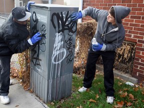 Graffiti removers Nicolaus Richard, right, and Jovon Kedding use lots of elbow grease and extra-strength cleansers to remove graffiti from Canada Post transfer boxes Friday November 12, 2010. They were participating in the Good Neighbour Services of St. Leonard's House on the day dedicated to random acts of kindness. (Windsor Star files)