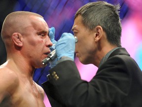 Mark Hominick, left, gets his eye checked after taking a blow to the head against Jose Aldo during the featherweight championship match at UFC 129 in Toronto in 2011. (THE CANADIAN PRESS/Nathan Denette)