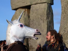 A man gestures as he watches the sun rise, as druids, pagans and revellers take part in a winter solstice ceremony at Stonehenge on December 21, 2012 in Wiltshire, England. Predictions that the world will end today as it marks the end of a 5,125-year-long cycle in the ancient Maya calendar, encouraged a larger than normal crowd to gather at the famous historic stone circle to celebrate the sunrise closest to the Winter Solstice, the shortest day of the year.  (Photo by Matt Cardy/Getty Images)