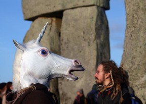 A man gestures as he watches the sun rise, as druids, pagans and revellers take part in a winter solstice ceremony at Stonehenge on December 21, 2012 in Wiltshire, England. Predictions that the world will end today as it marks the end of a 5,125-year-long cycle in the ancient Maya calendar, encouraged a larger than normal crowd to gather at the famous historic stone circle to celebrate the sunrise closest to the Winter Solstice, the shortest day of the year.  (Photo by Matt Cardy/Getty Images)