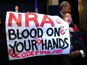 Medea Benjamin of CodePink is removed by a secretary personnel as she protests during NRA CEO and Executive Vice President Wayne LaPierre's news conference at the Willard Hotel prior to a news conference the association has scheduled December 21, 2012 in Washington, DC. This is the first public appearance that leaders of the gun rights group have made since a 20-year-old man used a popular assault-style rifle to slaughter 20 school children and six adults at Sandy Hook Elementary School in Newtown, Connecticut, one week ago.  (Photo by Alex Wong/Getty Images)