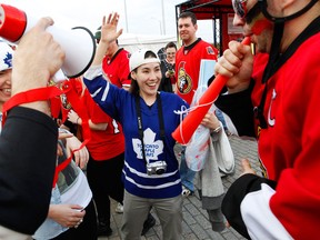 A Toronto Maple Leafs fan, centre, is heckled by Erik Faucon, right, and other Ottawa Senators fans outside Scotiabank Place in Ottawa. (Photo Jean Levac/Ottawa Citizen)