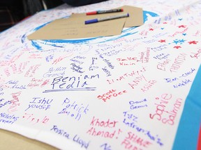 Students sign an oversized swim suit during a press conference at Holy Names High School about the upcoming FINA bid in Windsor on Thursday, December 6, 2012.           (TYLER BROWNBRIDGE / The Windsor Star)