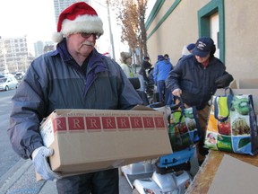The Windsor Goodfellows were handing out Christmas baskets Thursday, Dec. 13, 2012, at their downtown Windsor, Ont. location. Volunteer Larry Skinner hands out a package to a recipient during the event. (DAN JANISSE/The Windsor Star)