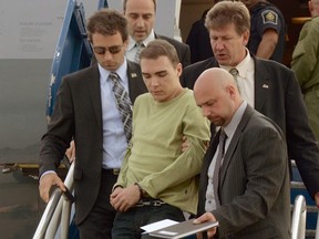 In this photo provided by Montreal Police, Luka Rocco Magnotta is taken by police from a Canadian military plane to a waiting van on Monday, June 18, 2012, in Mirabel, Quebec. Magnotta has pleaded not guilty in the body-parts case, appearing calm Tuesday in his first court session to face charges including first-degree murder. THE CANADIAN PRESS/Montreal Police