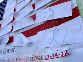 A U.S. flag is covered with numbers representing the people that died when a gunman opened fired at Sandy Hook Elementary School during a shooting rampage a day earlier, Saturday, Dec. 15, 2012, in Sandy Hook village of Newtown, Conn.
Photograph by: Julio Cortez, AP Photo)
