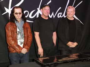 This Nov. 20, 2012 file photo shows members of the band Rush, from left, Geddy Lee, Neil Peart, and Alex Lifeson at the RockWalk induction of Rush at Guitar Center in Los Angeles. (Richard Shotwell/Invision/AP)