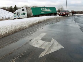 Tow truck crews work to free a transport truck that slide off the road on the E.C. Row southbound exit ramp at Huron Church Road in Windsor, Ont. on Thursday, December 27, 2012. Overnight snow made for driving delays across the region.         (TYLER BROWNBRIDGE / The Windsor Star)