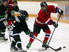 Anthony Tortola, left, of Tecumseh Powertech clears the puck against Jason Demelo of Tecumseh Ketchup during the Hospice Hockey Tournament at Tecumseh Arena Friday. (NICK BRANCACCIO/The Windsor Star)