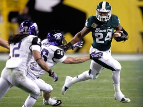 Michigan State running back Le'Veon Bell, right, is chased by TCU linebacker Joel Hasley, centre, as TCU cornerback Jason Verrett, left, pursues during the first half of the Buffalo Wild Wings Bowl in Tempe, Ariz. (AP photo/Paul Connors)