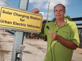 Klaus Dohring, President of Green Sun Rising, stands next to a electric vehicle charging station that is attached to a solar car park, Tuesday, August 9, 2011.  The charging station can charge electric cars such as the Prius and the Volt, as well as hybrid vehicles.