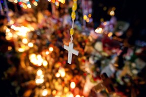 A cross hangs above a sidewalk memorial in honor of the Sandy Hook Elementary School shooting victims, Tuesday, Dec. 18, 2012, in Newtown, Conn. (AP Photo/David Goldman)