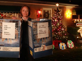 Grace Zebic holds two boxes that Dennis Grubka placed on his lawn after two decorative reindeer went missing, Monday, Dec. 10, 2012.  The notes on the boxes read 'To the person(s) who stole my reindeer...you forgot the boxes #%&@!!!'  (DAX MELMER/The Windsor Star)