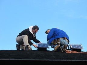 Paul Scott and Keith Torell, employees of Sure Seal Roofing & Siding, work on the solar panel-powered ventilation fan on Tuesday, Dec. 18, 2012. Monica Wolfson/The Windsor Star