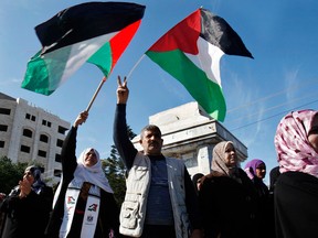 In this file photo, Palestinian women chant slogans during a protest calling for unity and to end the internal Palestinian division in Gaza City, Tuesday, Dec. 18, 2012. Arabic on the poster, left, reads," Palestine is above all," and at right, "the woman is the candle that burns for the country." (AP Photo/Adel Hana)